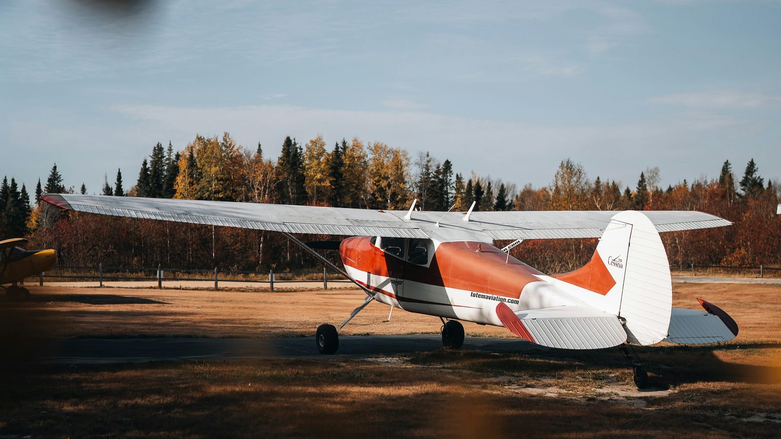 Small propeller aircraft parked on a grassy airfield for tailwheel training context.